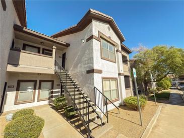 Low-angle shot of a two-story condo building with multiple units and a shared staircase and well maintained landscaping at 45 Maleena Mesa St # 327, Henderson, NV 89074