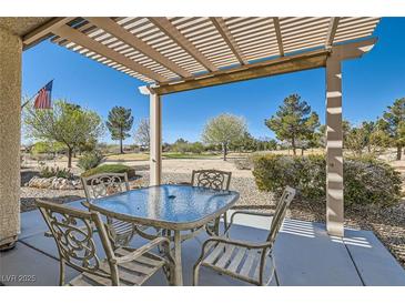 Inviting covered patio with a glass-topped table and seating overlooking lush landscaping at 7921 Fantail Dr, North Las Vegas, NV 89084