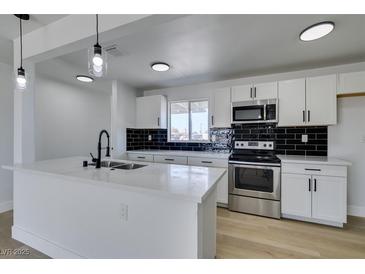 Modern kitchen with white cabinets, stainless steel appliances, an island and a black backsplash at 1225 Arrowhead Ave, Las Vegas, NV 89106