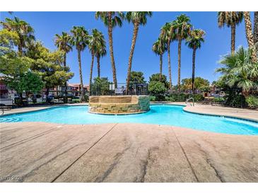 Relaxing community pool surrounded by mature palm trees and comfortable lounge chairs at 4730 E Craig Rd # 1093, Las Vegas, NV 89115