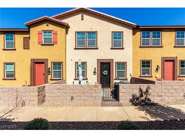 Charming townhome featuring a cozy walled front patio, colorful exteriors, and well-maintained landscaping at 703 Sleeping City Ave, Henderson, NV 89015