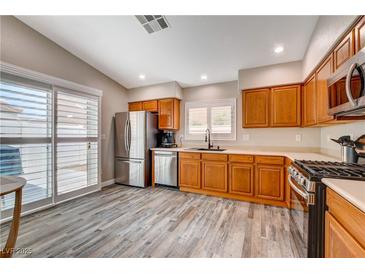 Bright kitchen featuring stainless steel appliances, wood cabinets, and sliding glass doors to the patio at 9292 Vervain Ct, Las Vegas, NV 89149