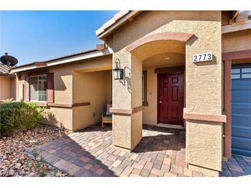 Inviting front entrance of a well-maintained home with a brick walkway and covered porch with red door at 2773 Chetco River St, Laughlin, NV 89029