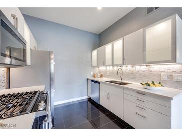 A modern kitchen boasts stainless steel appliances, sleek white cabinetry, and stylish backsplash at 2305 W Horizon Ridge Pkwy # 514, Henderson, NV 89052