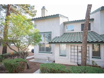 Charming stucco townhome featuring a unique green tile roof and well-manicured front yard at 2430 Old Forge Ln # 106, Las Vegas, NV 89121