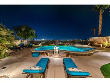 Inviting pool with spa, rock features, sun loungers, and a stunning city view at night at 2824 Soaring Peak Ave, Henderson, NV 89052