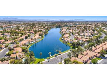 Stunning aerial view of a residential community built around a beautiful blue lake with mountain views in the background at 3125 N Buffalo Dr # 1136, Las Vegas, NV 89128