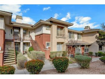 Inviting exterior showcasing a well-maintained two-story condo with stairs, landscaped bushes, and neutral paint colors at 908 Domnus Ln # 203, Las Vegas, NV 89144