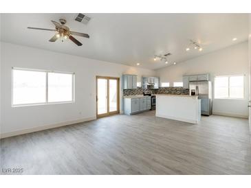 Open-concept living room and kitchen with stainless steel appliances, light blue cabinets, and wood-look floors at 2128 La Salle St, Las Vegas, NV 89106