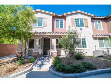 Charming townhome with a beautifully landscaped front yard and inviting covered entry with decorative stone accents at 8487 Insignia Ave # 105, Las Vegas, NV 89178