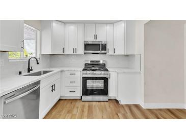 Bright kitchen featuring white cabinets, stainless steel appliances, and wood-look flooring at 451 Concord Way, Henderson, NV 89015