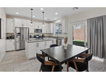 Bright eat-in kitchen with stainless steel appliances, white cabinetry, and gray countertops at 460 Accelerando Way, Henderson, NV 89011