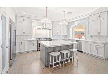 Bright, spacious kitchen featuring an island with seating, stainless steel appliances, and contemporary lighting at 6335 Mount Eden Ave, Las Vegas, NV 89139