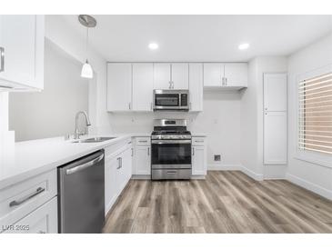 Bright kitchen features stainless steel appliances, white cabinets, and durable wood flooring at 10041 Arbuckle Dr, Las Vegas, NV 89134