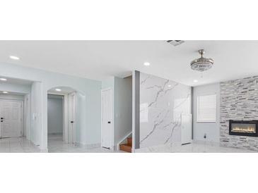 Bright, open-concept living room with marble floors, a stylish fireplace, and a decorative lighting fixture at 5516 Cory Pl, Las Vegas, NV 89107