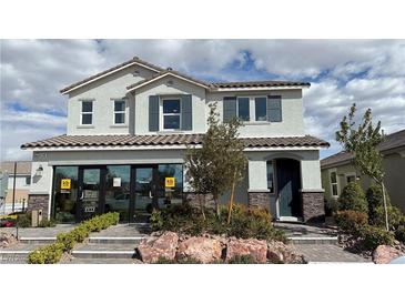 Two-story home with a neutral color scheme, dark shutters, stone accents, and manicured landscaping at 9190 Oakdale Ranch Ct, Las Vegas, NV 89139