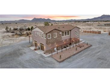 Stunning multi-story home with stone accents, desert landscaping, and mountain views at sunset at 2590 Luke St, Pahrump, NV 89060
