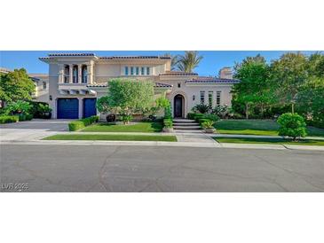 Elegant stucco home with dark blue garage doors, tile roof, and a professionally landscaped front yard at 3863 Glasgow Green Dr, Las Vegas, NV 89141