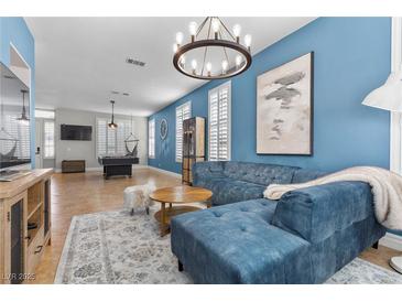 Bright living room with blue accent wall, modern lighting, plush sectional sofa, and elegant rug at 9475 Castillana Ct, Las Vegas, NV 89147