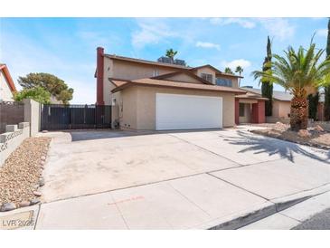 Two-story home boasts an attached two-car garage, desert landscaping, and concrete driveway on a sunny day at 1009 N Tenaya Way, Las Vegas, NV 89128