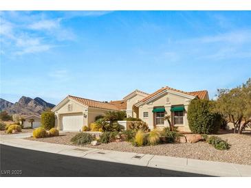 Charming single-story home with a desert landscape, attached garage and tile roof against a mountainous backdrop at 10548 Findlay Ave, Las Vegas, NV 89134