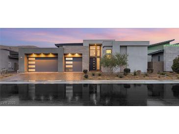 Modern home with a three-car garage, sleek design, and professional landscaping reflecting in the wet street at 10794 White Clay Dr, Las Vegas, NV 89135