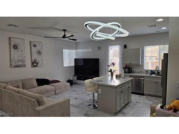 Bright living room featuring modern light fixture, large sectional sofa, and an island bar that leads to the kitchen at 3634 Surfboard Ct, Las Vegas, NV 89147