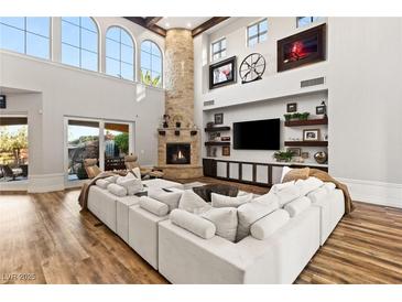 Bright living room with soaring ceilings, a stone fireplace, and a large comfortable sectional sofa at 8455 Stange Ave, Las Vegas, NV 89129