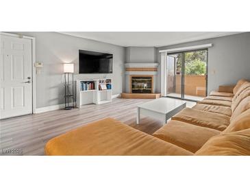 Bright living room featuring a fireplace, sliding glass doors, and a comfortable, modern sofa at 2451 N Rainbow Blvd # 2067, Las Vegas, NV 89108