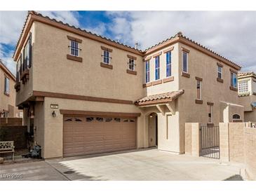 Two-story tan home with a two-car garage, tiled roof, and gated front porch at 682 Baffin Island Rd, Henderson, NV 89011