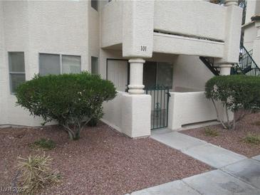 Exterior shot of a stucco condominium building with landscaped front yard and gated patio at 1341 Cinder Rock Dr # 101, Las Vegas, NV 89128