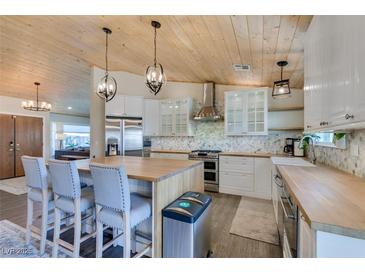 Bright kitchen boasts wood ceiling, island with seating, stainless steel appliances, and stylish countertops at 3083 Paintedhills Ave, Las Vegas, NV 89120