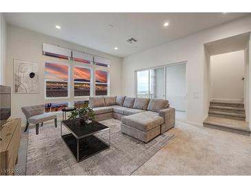 Bright living room with large windows showcasing a city view and a comfortable gray sectional sofa at 3346 Esker Ridge Ave, Henderson, NV 89044