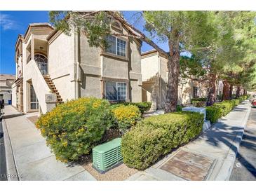 View of the condo's exterior featuring manicured landscaping with mature trees and shrubbery at 3660 Renovah St # 204, Las Vegas, NV 89129