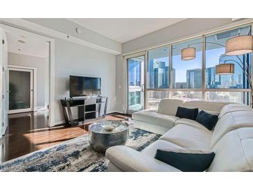 Modern living room featuring a white sectional sofa and stunning city views through large windows at 4525 Dean Martin Dr # 2001, Las Vegas, NV 89103