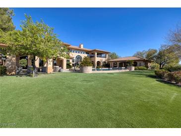Expansive backyard with lush lawn, pool, and basketball court, perfect for outdoor entertaining and recreation at 9801 Orient Express Ct, Las Vegas, NV 89145