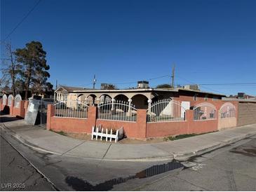 Charming single-story home featuring arched supports and a decorative metal fence surrounding the front yard at 2700 Spear St, North Las Vegas, NV 89030