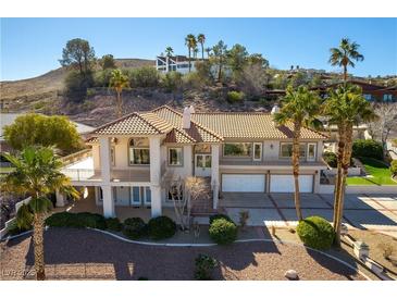 Stately home with a tile roof, palm trees, and a three-car garage on a sunny day at 380 Claremont St, Boulder City, NV 89005