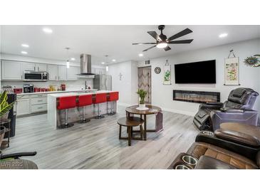 Open-concept living space featuring an island with seating, modern fireplace, and sleek, neutral decor at 5097 Indian River Dr # 172, Las Vegas, NV 89103