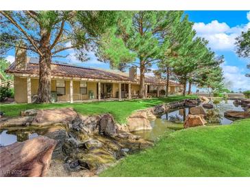 Stunning backyard view with lush landscaping, water feature and mature trees providing ample shade at 7803 Canoe Ln, Las Vegas, NV 89145