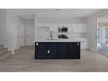 Modern kitchen featuring white cabinets, subway tile backsplash, and a large island with a black base at 793 Vortex Ave, Henderson, NV 89002