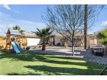This backyard features a lush lawn, desert landscaping, a custom patio, and a charming playset at , Las Vegas, NV 89121