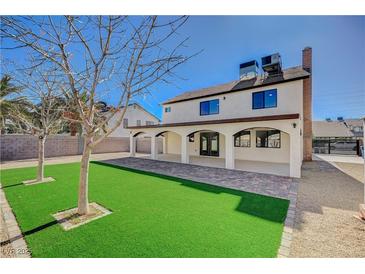 Expansive backyard with lush artificial turf and a covered patio, perfect for entertaining guests outdoors at 1904 Roxbury Ln, Las Vegas, NV 89119
