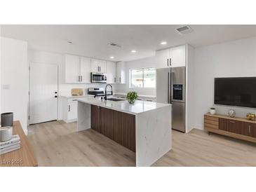 Modern kitchen features stainless appliances, white cabinets, and a large center island with marble countertop at 2368 Winterwood Blvd, Las Vegas, NV 89142