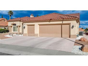 Beige home with a red tile roof and a three car garage with a concrete driveway at 3012 Anna Bay Dr, Las Vegas, NV 89134