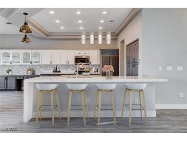 Modern kitchen boasts white cabinets, quartz countertops, mosaic backsplash, and stainless steel appliances at 3012 Anna Bay Dr, Las Vegas, NV 89134
