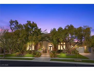 Stunning home exterior featuring a wrought iron gate and mature landscaping at dusk at 3680 Belvedere Park Ln, Las Vegas, NV 89141