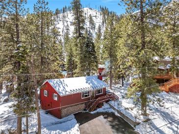 Charming cabin with snow covered roof nestled among tall pine trees and a mountain backdrop at 4165 Mont Blanc Way, Mount Charleston, NV 89124