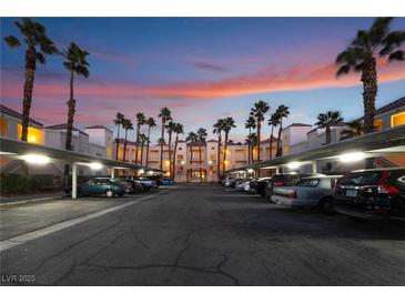 Exterior shot of parking lot with covered parking and palm trees at sunset at 5000 Red Rock St # 120, Las Vegas, NV 89118