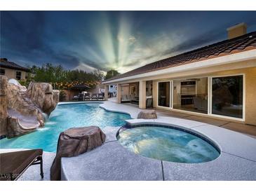 Backyard pool features a rock slide, spa, and a covered patio with lounge seating at 5870 N Durango Dr, Las Vegas, NV 89149